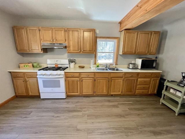 kitchen with a sink, under cabinet range hood, white gas stove, and light countertops