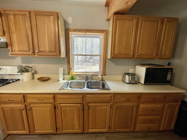 kitchen with black microwave, a sink, light countertops, white gas range oven, and extractor fan