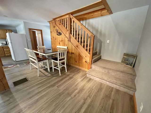 dining area with stairs, visible vents, and wood finished floors