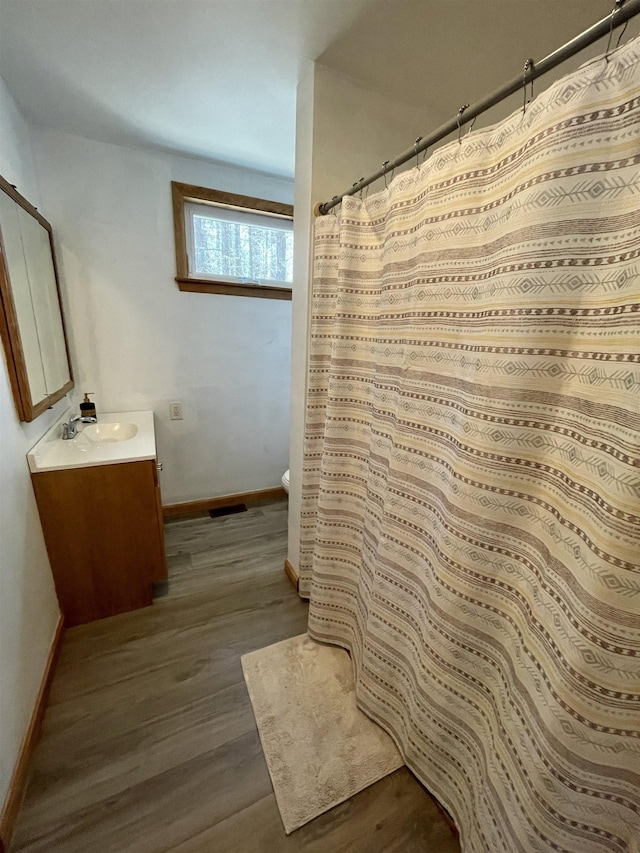 bathroom featuring vanity, curtained shower, wood finished floors, toilet, and baseboards