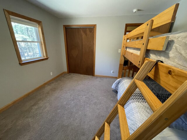 bedroom with baseboards, carpet, and a closet