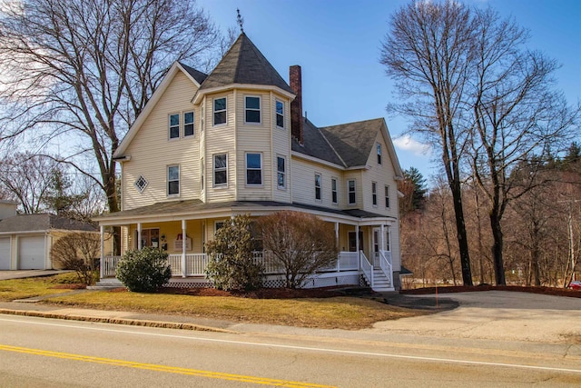 victorian home featuring a porch, driveway, and a chimney