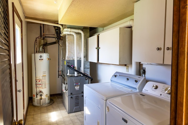 laundry area featuring heating unit, cabinet space, water heater, and washer and dryer
