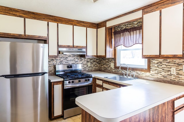 kitchen featuring decorative backsplash, a sink, light countertops, under cabinet range hood, and stainless steel appliances