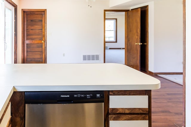 kitchen featuring light countertops, stainless steel dishwasher, wood finished floors, and visible vents