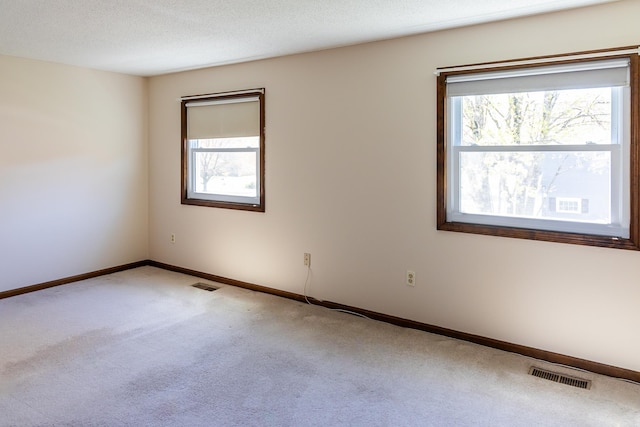 empty room with visible vents, carpet floors, and a wealth of natural light