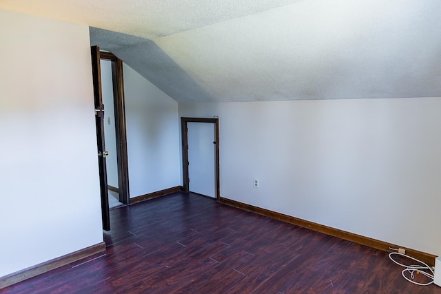 additional living space featuring baseboards, vaulted ceiling, and dark wood-style floors