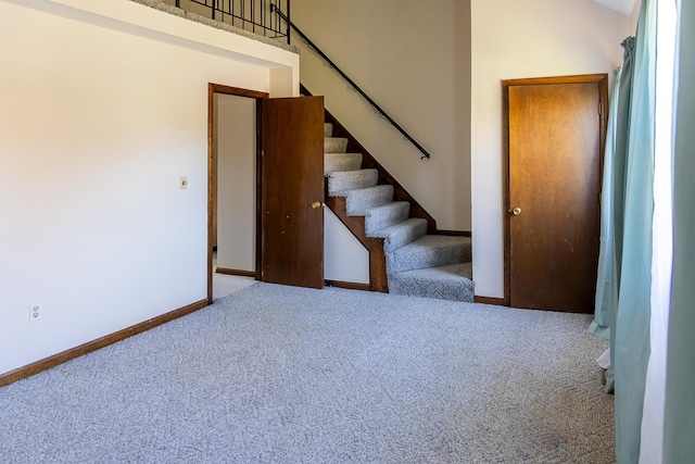 interior space featuring baseboards, carpet, and a towering ceiling