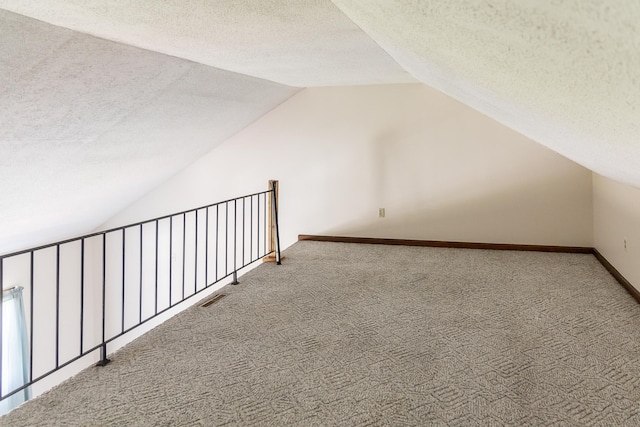 bonus room featuring carpet floors, visible vents, baseboards, a textured ceiling, and vaulted ceiling