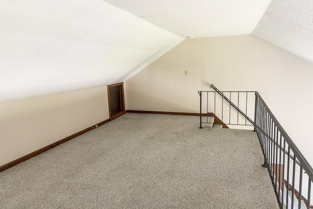additional living space with baseboards, vaulted ceiling, and light carpet