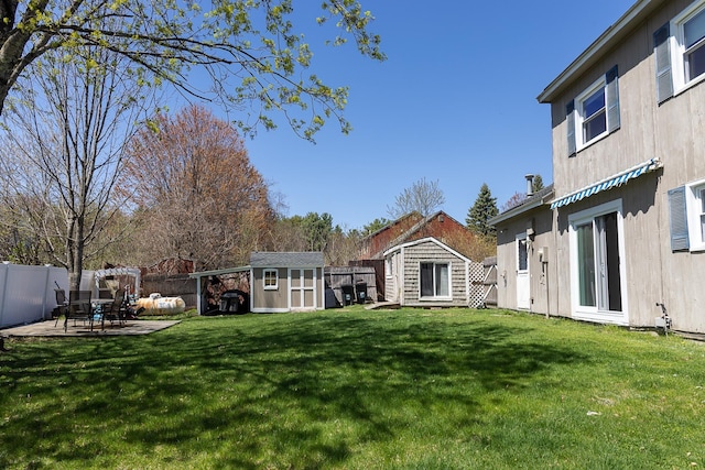 view of yard featuring a patio, a fenced backyard, a shed, and an outbuilding