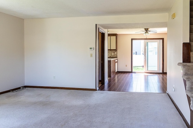 empty room with baseboards, ceiling fan, and dark carpet
