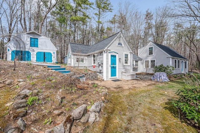 rear view of property featuring an outdoor structure and a shingled roof