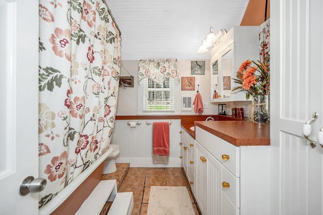 full bath with vanity, tile patterned flooring, curtained shower, toilet, and a wainscoted wall