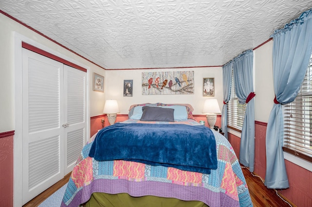 bedroom with wood finished floors, an ornate ceiling, and a closet