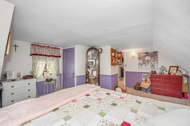 bedroom featuring carpet flooring, lofted ceiling, and a wainscoted wall