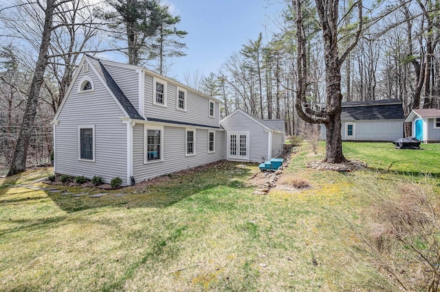 back of house with french doors, a lawn, a storage shed, an outbuilding, and a shingled roof