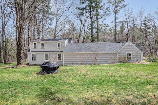 back of house featuring a yard and a shingled roof