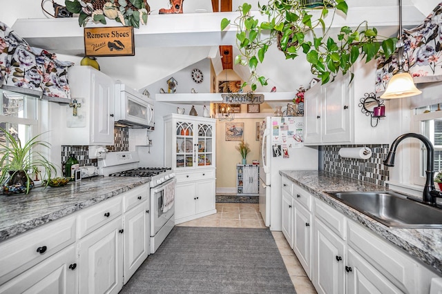 kitchen featuring a sink, tasteful backsplash, white appliances, and white cabinetry