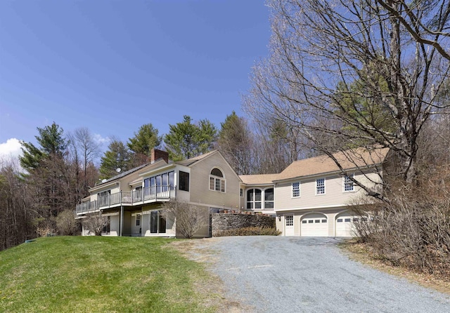 view of front facade featuring a chimney, a sunroom, a garage, gravel driveway, and a front lawn