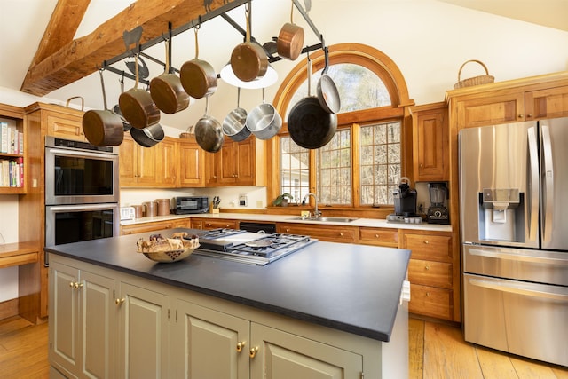 kitchen featuring a sink, stainless steel appliances, light wood-type flooring, a kitchen island, and vaulted ceiling