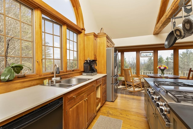 kitchen featuring light countertops, brown cabinets, a sink, light wood finished floors, and appliances with stainless steel finishes
