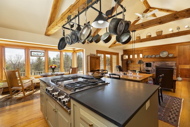 kitchen featuring a kitchen island, vaulted ceiling with beams, open floor plan, and stainless steel gas stovetop