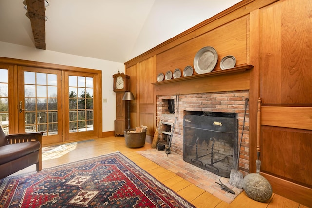living area with wood-type flooring, vaulted ceiling, and a brick fireplace