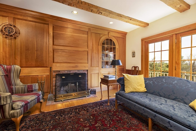 living area with beam ceiling, a fireplace, recessed lighting, a wainscoted wall, and hardwood / wood-style flooring