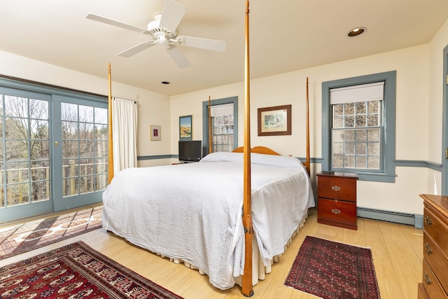 bedroom featuring wood-type flooring, ceiling fan, a baseboard heating unit, and multiple windows