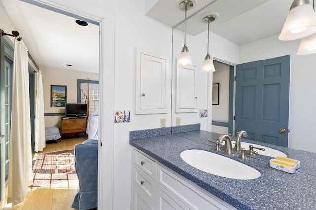 ensuite bathroom with vanity, ensuite bath, and wood finished floors