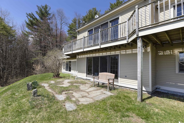 rear view of property featuring a patio area, a balcony, and a yard