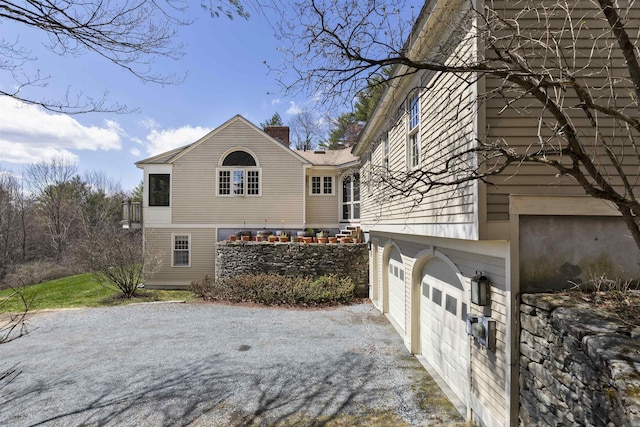 view of side of property featuring an attached garage, driveway, and a chimney