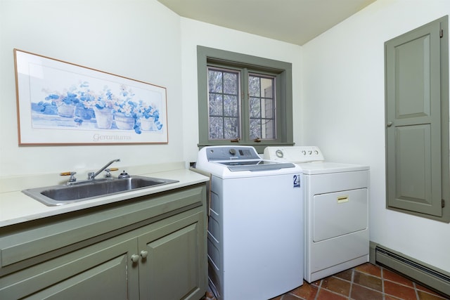laundry room with cabinet space, a sink, baseboard heating, dark tile patterned flooring, and washer and clothes dryer
