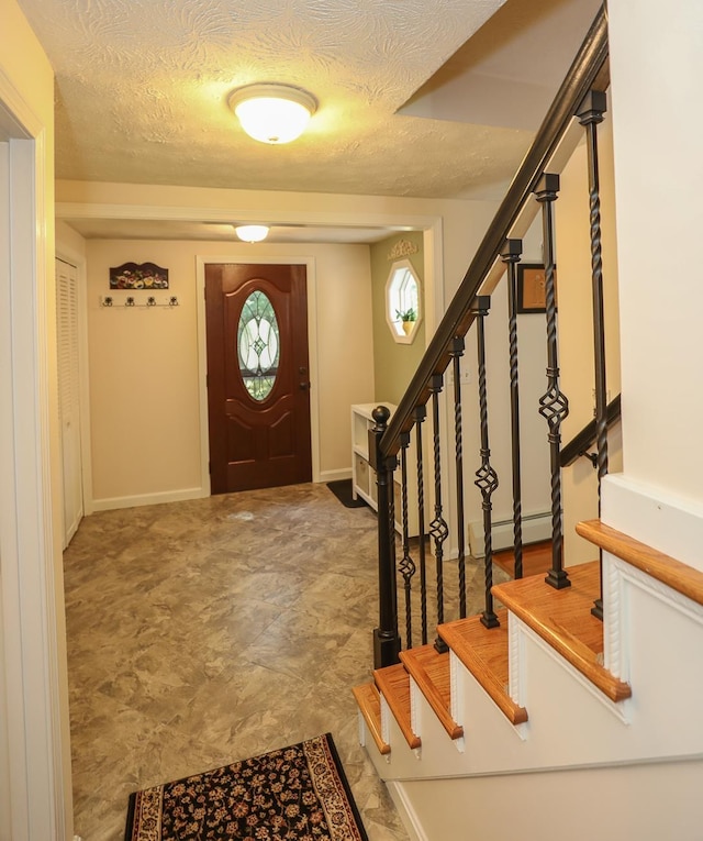 foyer entrance featuring baseboards, a textured ceiling, and stairs