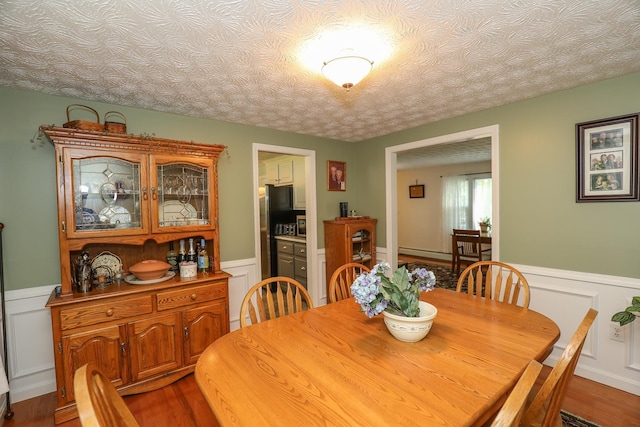 dining space featuring a decorative wall, wainscoting, and wood finished floors
