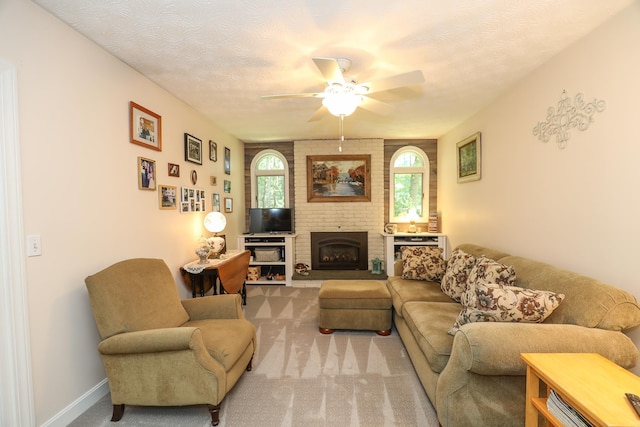 carpeted living area with ceiling fan, a brick fireplace, and a textured ceiling