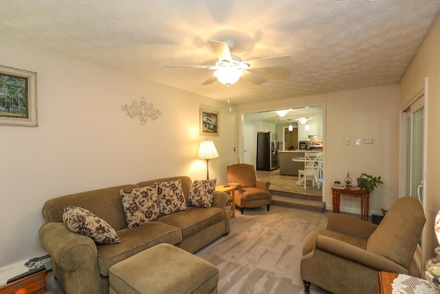 living area with a textured ceiling, ceiling fan, and light colored carpet