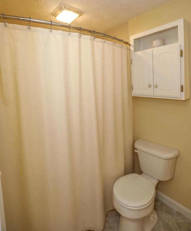 full bathroom with baseboards, a textured ceiling, and toilet