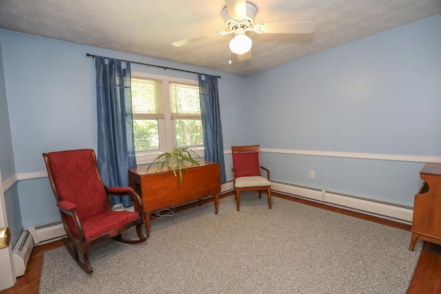 sitting room with ceiling fan, wood finished floors, and baseboard heating