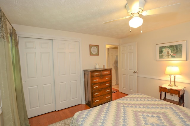 bedroom with a ceiling fan, a textured ceiling, wood finished floors, and a closet