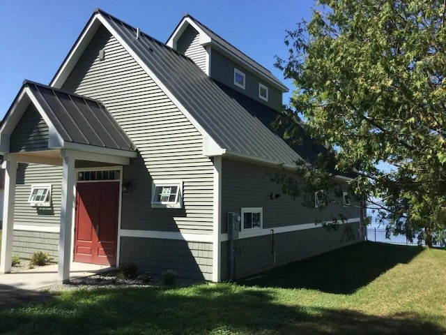 view of property exterior featuring a standing seam roof, a yard, and metal roof