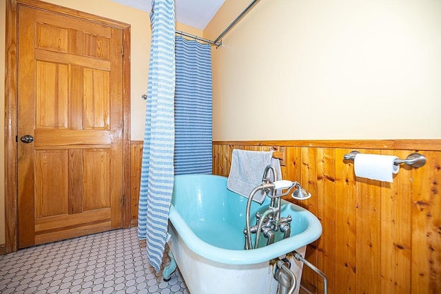 full bath featuring a freestanding tub, wainscoting, and wood walls
