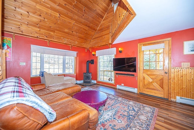 living area with lofted ceiling, a healthy amount of sunlight, baseboard heating, and a wood stove