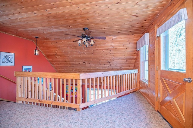 additional living space featuring carpet flooring, wooden walls, a ceiling fan, wooden ceiling, and vaulted ceiling