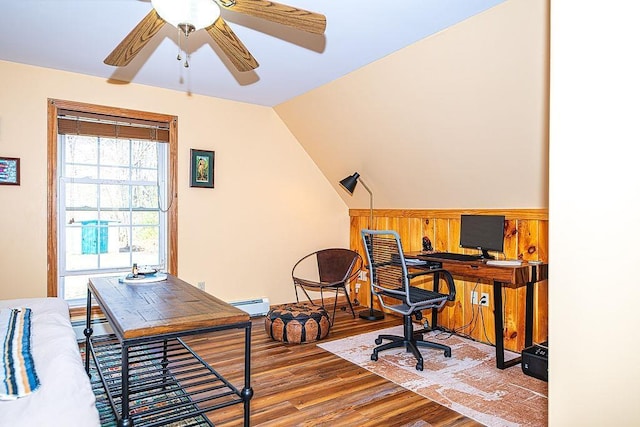home office featuring a ceiling fan, wood finished floors, baseboard heating, and vaulted ceiling