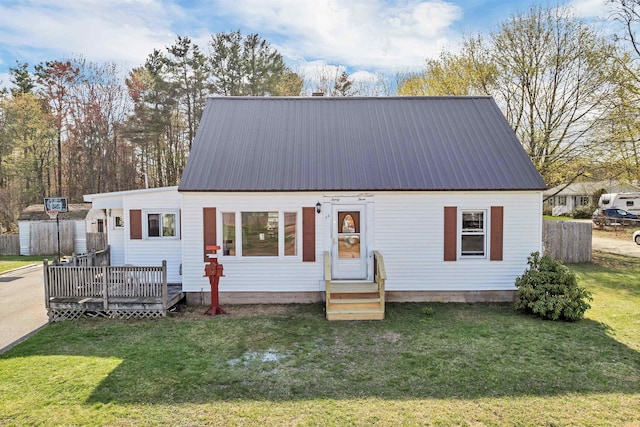 view of front of home with a front yard, metal roof, a deck, and entry steps