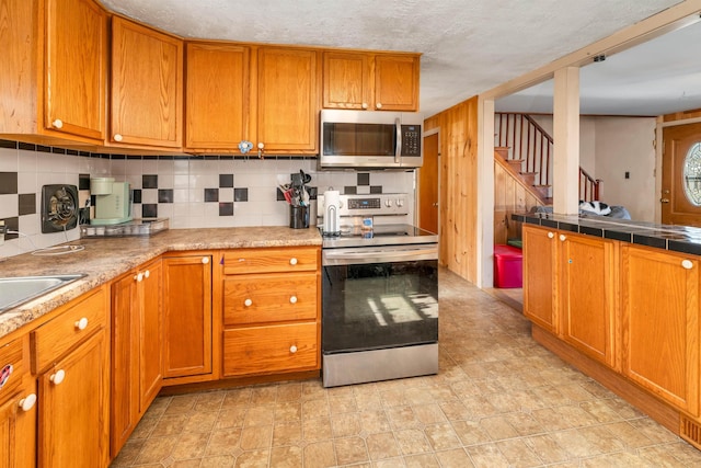 kitchen featuring tasteful backsplash, stainless steel appliances, and brown cabinets