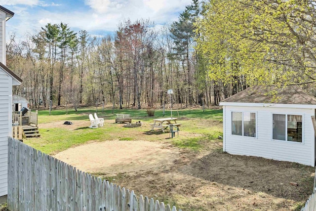 view of yard with fence, an outbuilding, and an outdoor fire pit