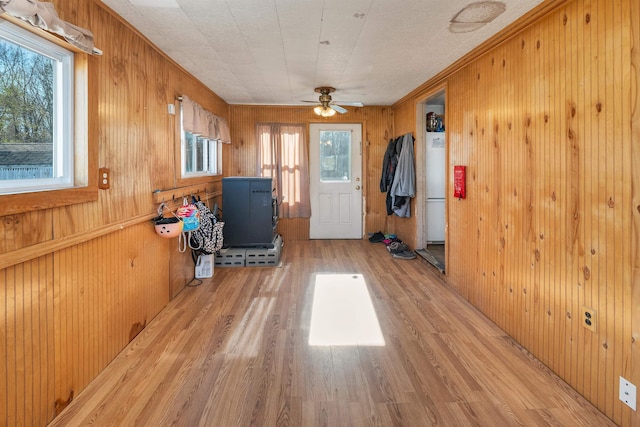 entryway with wooden walls, ceiling fan, and light wood-type flooring